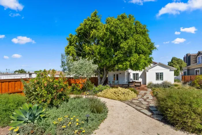 Charming cottage with lush garden, shaded deck, and stone path