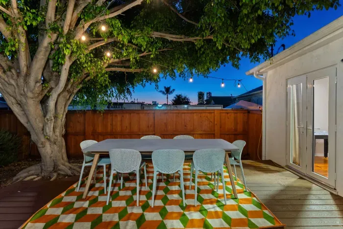 Twinkle-lit patio with 8-seat dining under a majestic tree and bold rug