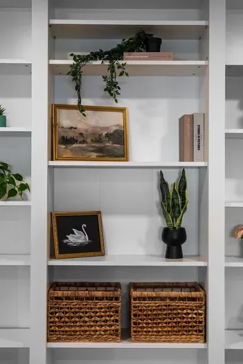 Curated built-ins with art, greenery, and woven baskets for chic storage