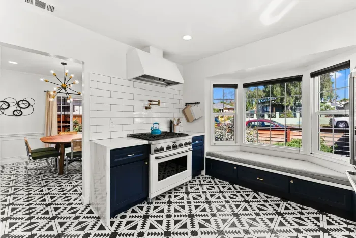 Bright kitchen with bay-window bench, gas range, and bold tile floor
