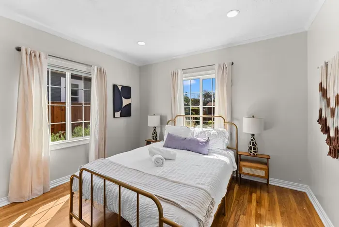 Bright, serene bedroom with brass bed, hardwood floors and cozy linens.
