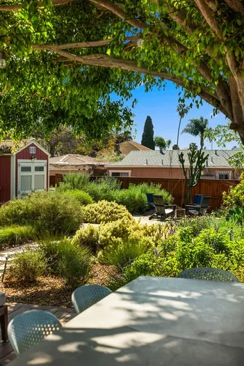 Lush garden oasis with shaded dining, paths, and cozy seating area