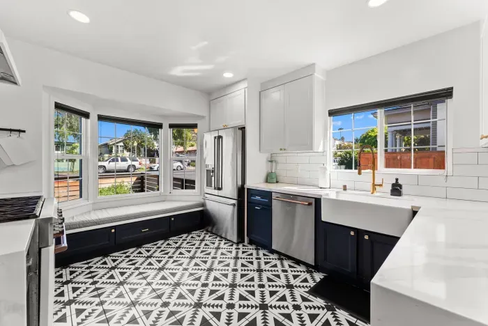 Sunlit kitchen with bay-window bench, farmhouse sink, and patterned tile.