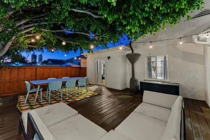 Cozy deck under a leafy canopy with dining for 6 and twinkle lights