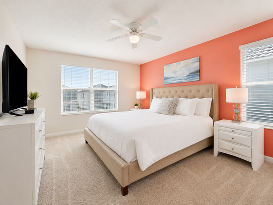 King suite with coral accent wall and white furniture