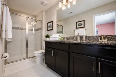 Bright spa-like bathroom with granite double vanity and glass shower