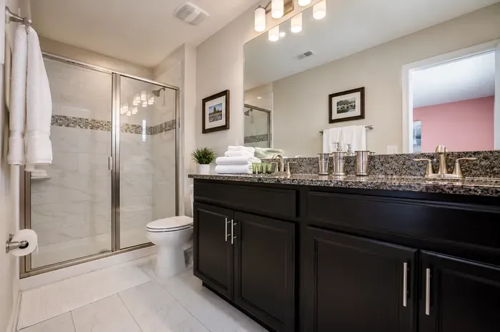 Bright spa-like bathroom with granite double vanity and glass shower