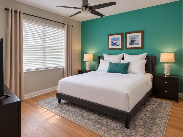 Bright, stylish bedroom with teal accent wall and plush queen bed