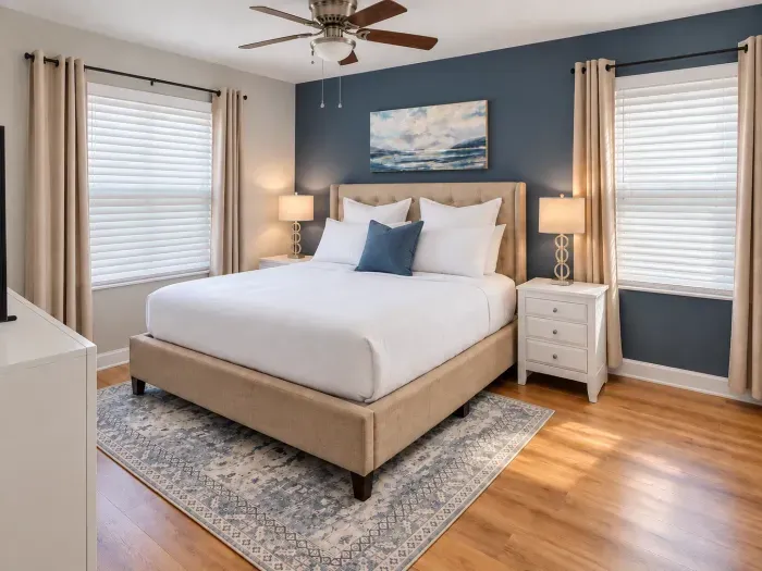 Bright, stylish king bedroom with navy accent wall and cozy finishes